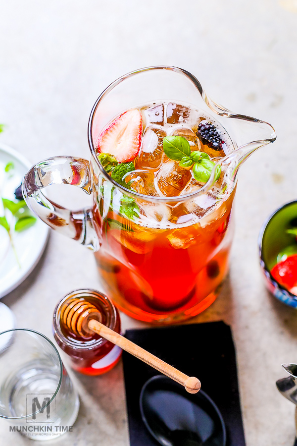 Black iced tea in a pitcher and garnished with mint, strawberry and blackberry. 
